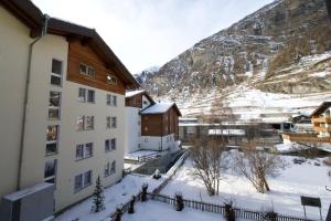 a building in the snow next to a mountain at Studio NINNI in Zermatt