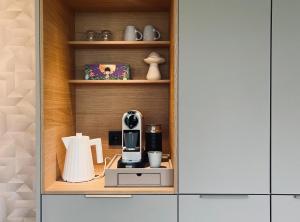a kitchen with a cupboard with a coffee maker in it at Wiltsangh Texel Tuinsuite Light in De Waal