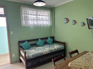 a bedroom with a bed with blue pillows and a table at Apto em frente ao mar prédio redondo linda vista in Peruíbe