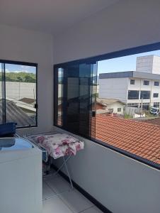 a room with two large windows and a small table at Casa de férias Branvek in Brusque