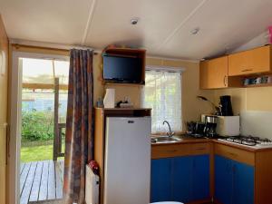 a kitchen with a refrigerator and a tv on top of it at Mobilhome Super Titania - 3 Bedrooms - Family Camping JF102 in Les Mathes +17 photos