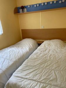 a bed with white sheets sitting in a room at Mobilhome Super Titania - 3 Bedrooms - Family Camping JF102 in Les Mathes