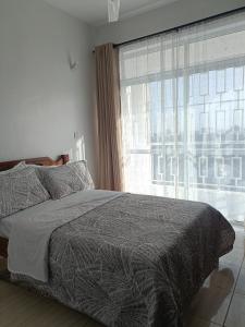 a bedroom with a bed and a large window at Sharz place - Mombasa in Mombasa +20 photos