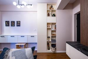 a living room with white cabinets and a table at Stylish Apartment Otopeni in Otopeni