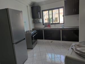 Il comprend une cuisine avec des placards noirs et du carrelage blanc. dans l'établissement Appartement de standing, à Casablanca 17 autres photos