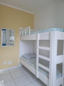 um beliche branco num quarto com um espelho em Doce Vida Ubatuba - Próximo as Praias, Centro e Restaurantes em Ubatuba