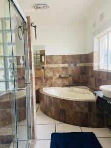 a large bathroom with a tub and a sink at Birch stay in Kempton Park
