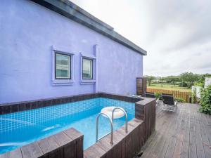 a swimming pool next to a blue house at Jeju Love Stay Purple in Jeju
