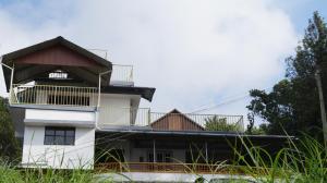 a white building with a balcony and trees at Grace Inn Munnar Homestay in Munnar