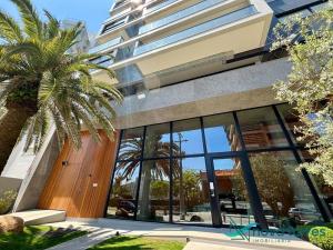 a building with a palm tree in front of it at Loft Industrial - Edifício Vista Mare apto novo in Torres