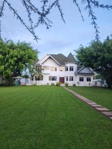 una gran casa blanca con césped verde en Amala villas, en Arusha