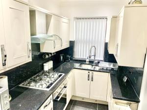 a white kitchen with white cabinets and a sink at Urba Luxury Stays 4Bed Sheffield University in Neepsend +20 photos