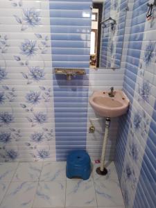 y baño con lavabo y paredes de azulejos azules y blancos. en Awadh Nikunj Homestay, en Ayodhya