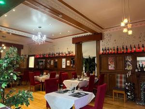 a restaurant with tables and red chairs and a bar at Gothenburg Hotel in Rosyth