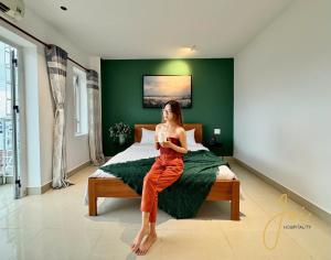 a woman sitting on a bed in a bedroom at Joi Hospitality - Anthony in Vung Tau