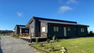 a black house with a porch on a grass field at Cabañas Renacer Puerto Varas in Puerto Varas