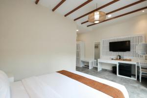 a white bedroom with a bed and a flat screen tv at Flamingo Aquila in Uluwatu