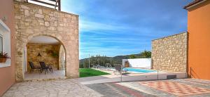 a stone house with a patio and a swimming pool at Villa Silvia by Andrian Villas in Kalamítsion Alexándrou