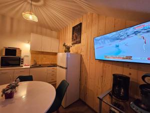 a kitchen with a table and a tv on a wall at Gite Eglantine 2 à 6 personnes avec SPA et salle de jeux dans la résidence in Ventron