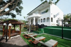 a white house with a green fence and a yard at Flamingo Aquila in Badung