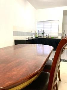 una cucina con un tavolo di legno e due sedie di Isyfaq Homestay Seremban Rahang 3 Bedrooms a Seremban Altre 11 foto