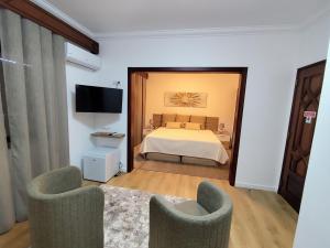 a bedroom with a bed and two chairs and a television at Residencial Pôr do Sol in Couço