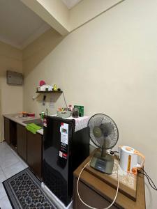 a room with a kitchen with a refrigerator and a fan at DHW Homestay in Simpang Ampat Semanggol +8 photos