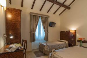 a bedroom with two beds and a desk and a window at Al Casaletto Hotel in Settecamini