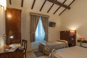 a bedroom with two beds and a desk and a window at Al Casaletto Hotel in Settecamini