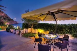 a patio with a table and chairs and an umbrella at Hotel Parco Smeraldo Terme in Ischia