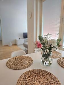 ein Tisch mit einer Vase mit Blumen darauf in der Unterkunft City apartment Kuopio Satamankulma, free parking, wifi & sauna in Kuopio + 2 Fotos