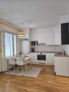 eine Küche mit weißen Schränken und einem Tisch und Stühlen in der Unterkunft City apartment Kuopio Satamankulma, free parking, wifi & sauna in Kuopio