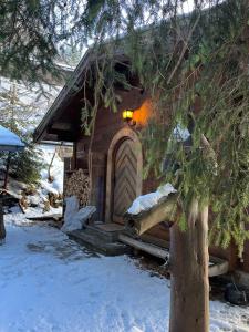 drewniany domek z drewnianymi drzwiami w śniegu w obiekcie Walters Hütte w mieście Tulfes