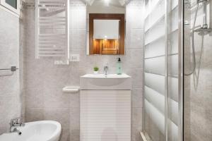 Un baño blanco con lavabo y espejo. en White Flat Sanniti, en Roma 7 fotos más