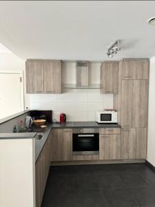 una cucina con armadi in legno e forno a microonde di Le Refuge Historique WIFI - Parking - Confort a Bruxelles Altre 3 foto