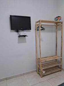 a flat screen tv sitting on a wall next to a shelf at Suítes flor de Mandacaru in Piranhas