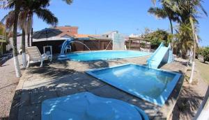 a swimming pool with a slide next to a house at Pousada BELEZAS DE LAGUNA in Laguna