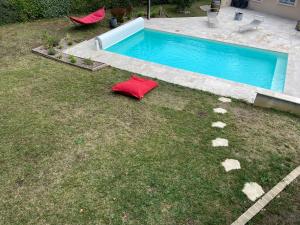 a swimming pool with a red pillow in the grass at Le Logis de la Forêt in Le Poinçonnet +3 photos