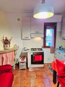 a kitchen with a stove and a red couch at La Casa di Brandolice in Vivo dʼOrcia