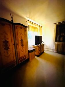 a living room with a tv and a dresser and a room with a tv at Căsuța din povești in Oradea +12 photos