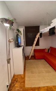 a living room with a red couch and a loft bed at Petit Baqueira 1500 a pie de pistas in Baqueira-Beret