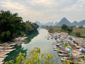 a group of boats lined up on a river with umbrellas at shadow climers guest house in Yangshuo