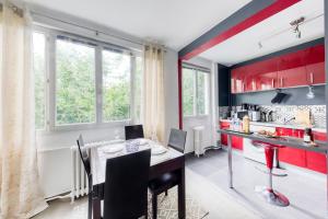 a kitchen with red cabinets and a table and chairs at L'incontournable de Paris la Défense in Puteaux