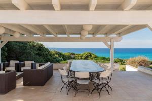 eine Terrasse mit Tisch und Stühlen und dem Meer in der Unterkunft Villa La Bitta in Badesi