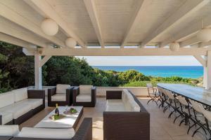 eine Außenterrasse mit einem Tisch, Stühlen und Meerblick in der Unterkunft Villa La Bitta in Badesi