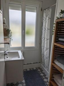 ein Badezimmer mit Waschbecken und Fenster in der Unterkunft Maison de vacances cosy in Avranches