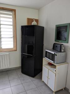 a black refrigerator in a kitchen with a microwave at Maison de vacances cosy in Avranches +3 photos