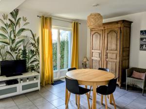 a dining room with a wooden table and chairs at Maison de vacances cosy in Avranches