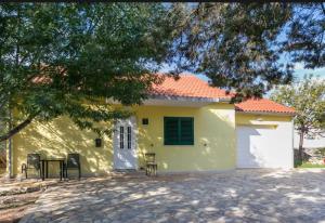 ein gelbes Haus mit einem Tisch und Stühlen davor in der Unterkunft HOLIDAY HOUSE Ose in Mirce