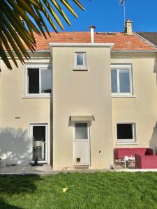 a white house with red furniture in a yard at Studio avec cuisine, salle de bain et garage privé proximité 24h in Le Mans